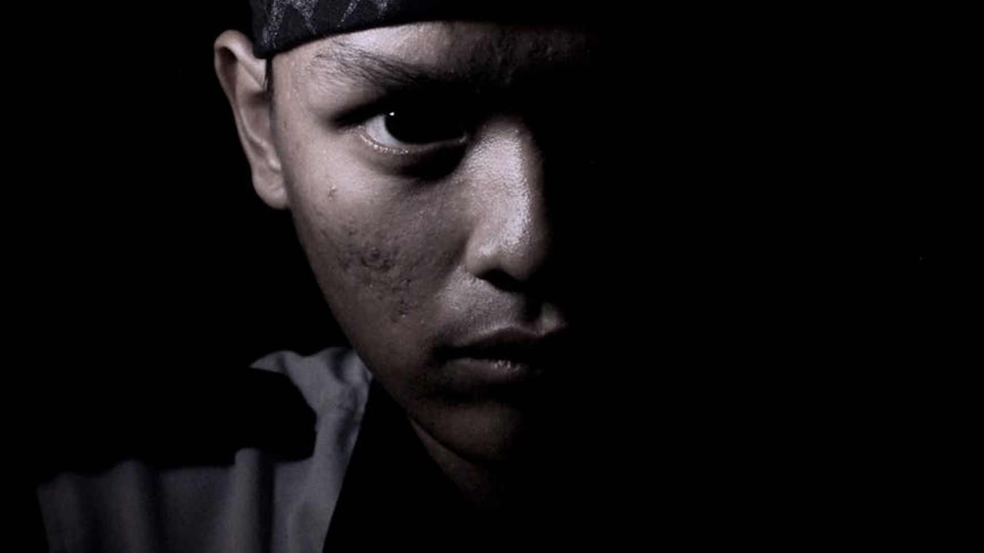 Silhouette of a man in a powerful stance against a dark, textured background.